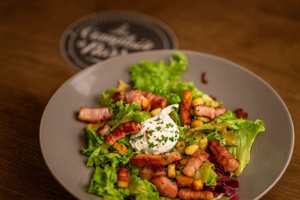 Salade lyonnaise : lardons poêlés, œuf mollet, croûtons